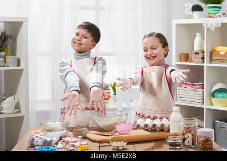 Girl and boy cooking in home kitchen. Children show hands with flour. Stock Photo