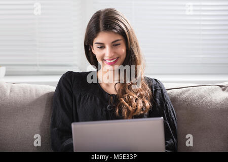 Close-up Of A Smiling Young Woman Using Laptop At Home Stock Photo