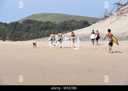 A group of surfers walking on the beach in Coffee Bay at the Indian Ocean in the Eastern Cape at the Wild Coast of South Africa carrying surfboards an Stock Photo