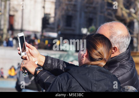 Man and woman composing a selfie on a smartphone in Trafalgar Square, London Stock Photo