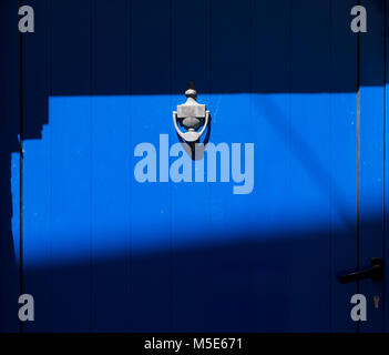 Blue door with knocker in sunlight and shadow Stock Photo