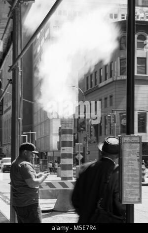 New York, NY, USA - June 06, 2015:Steam coming out of Greeley Square and the intersection West 32 in Manhattan in the spring. Traffic of cars and crow Stock Photo