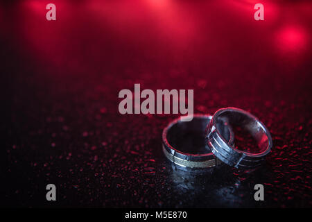 Two golden wedding rings on red background. Space for copy. Love and marriage concepts.