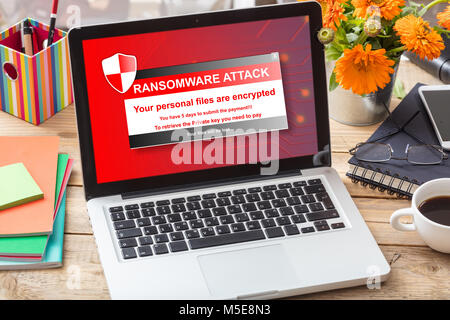 Ransomware attack message on a computer screen on a wooden office desk Stock Photo