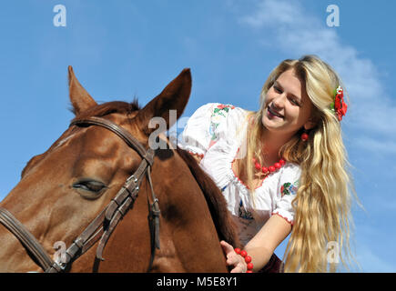 teenage girl with long hair horseback riding in sunny day Stock Photo