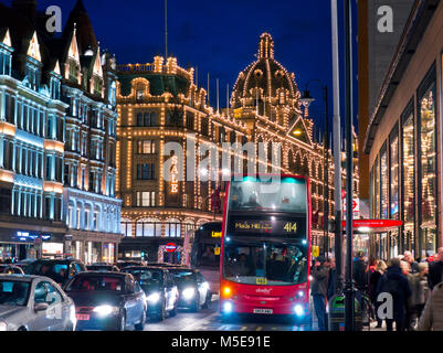 KNIGHTSBRIDGE WINTER SALE Harrods department store at night lit 'Sales’ sign shoppers red bus blur traffic Brompton Road Knightsbridge London SW1 Stock Photo
