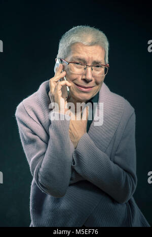 Senior woman receiving painful news of tragedy over her cell phone Stock Photo