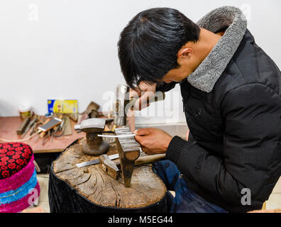 a sliversmith working on an ornament for the Mosuo minority dress Stock Photo