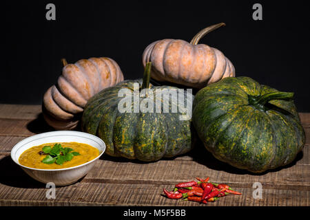 Healthy eating ingredients picture with collection of four hand picked fresh pumpkins, different colors, big and small, bowl of soup and red chillies Stock Photo