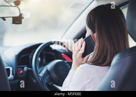 Woman using smart phone while driving a car Stock Photo