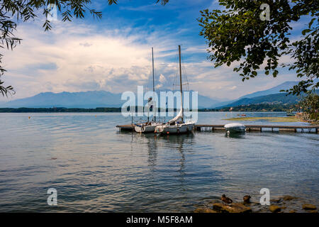 Two yachts moored at small wooden pier under beautiful sky on Lake Viverone in Piedmont, Northern Italy. Stock Photo