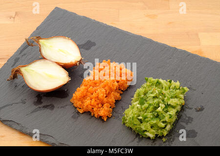 Mirepoix, tricolor vegetables arranged on slate black plate,  concept for haute cuisine, from above, minced orange carrot, green celery and onion Stock Photo
