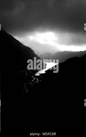 Lake in the alps mountains, illuminated by a ray of sunshine during a thunderstorm, black and white Valle Formazza, Piedmont, Italy Stock Photo