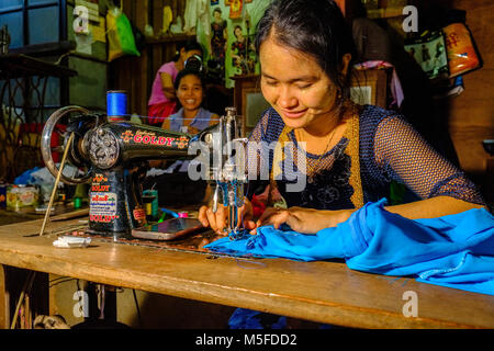 A young woman is working with a sewing machine in the market of town Stock Photo