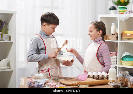 Girl and boy cooking in home kitchen. The boy breaks the egg. Healthy food concept Stock Photo