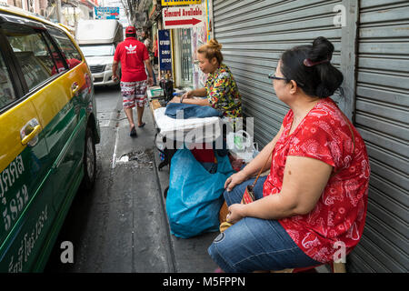A woman while sewing on the sidewalk of a bangkok street, Thailand Stock Photo
