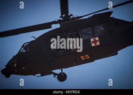 A U.S. service member rides a Sikorsky UH-60 Black Hawk air-lifting a patient for emergency care during a disaster relief rescue exercise in support of Cobra Gold 2018 in Chachoengsao province, Kingdom of Thailand, Feb. 21, 2018. Drills such as this one provide a venue for both United States and partner nations to advance interoperability and increase partner capacity in planning and executing complex and realistic multinational force and combined task force operations. CG18 is an annual exercise conducted in the Kingdom of Thailand and runs from Feb. 13-23 with seven full participating nation Stock Photo