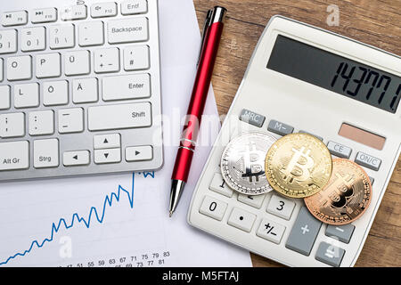 bitcoin crypto currency financial concept golden silver copper coins on calculator wooden desk with keyboard and red pencil Stock Photo