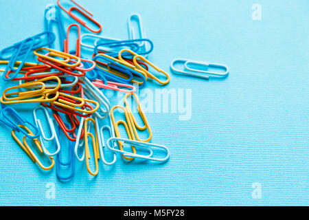 colorful paper clips on a blue background. Stock Photo