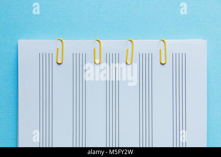 sheet Notepad and yellow clips on a blue background. Stock Photo
