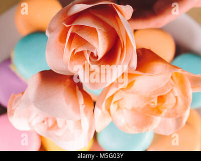 beautiful gentle rose created for the decor of desserts and cakes on a background of bright macarons Stock Photo