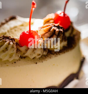 Red glace cherry on top of cake, macro, closeup, selective focus. Cake decoration detail, white cream, top with cherries, sweet treat. Stock Photo