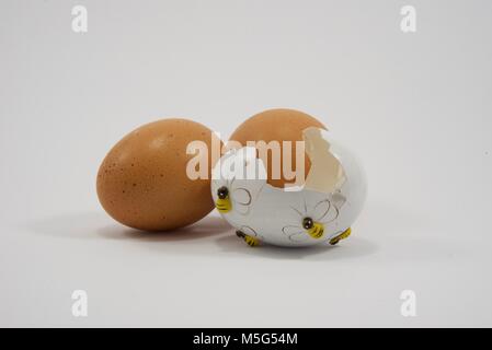 One broken decorative Easter egg and two chicken eggs Stock Photo