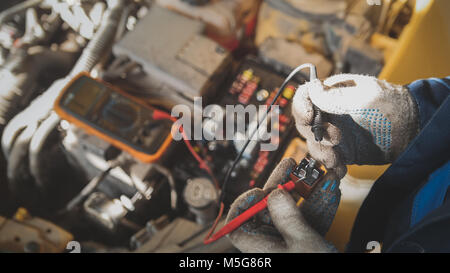 Mechanic works with car electrics - electrical wiring, voltmeter Stock Photo
