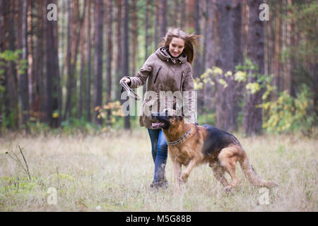 Young attractive woman playing with German Shepherd dog outdoors in the autumn park Stock Photo