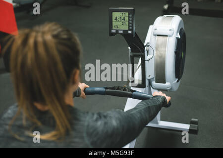 Muscular woman exercising on rowing machine Stock Photo