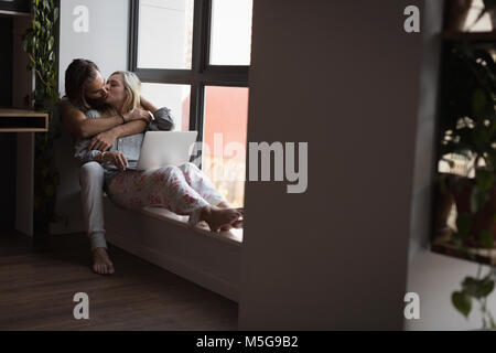 Couple kissing each other while using laptop Stock Photo