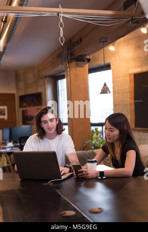 Business colleagues discussing over laptop at desk Stock Photo