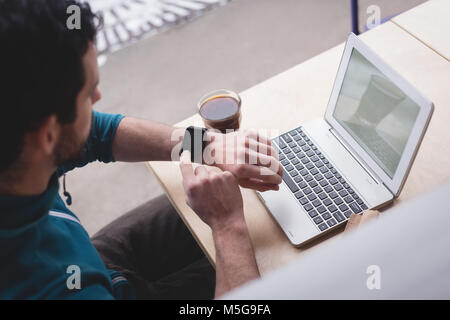 Man using smartwatch in cafe Stock Photo