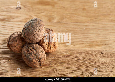 A stack of hard shells of walnuts piled together on light grey fabric cotton napkin and isolated on rustic wooden background, copy space, shallow dept Stock Photo