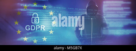 Composite image of male hacker in black hoodie standing Stock Photo
