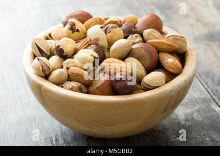 Assorted mixed nuts in bowl on wooden table Stock Photo