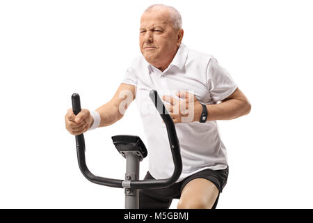 Mature man working out on an exercise bike and having a heart attack isolated on white background Stock Photo