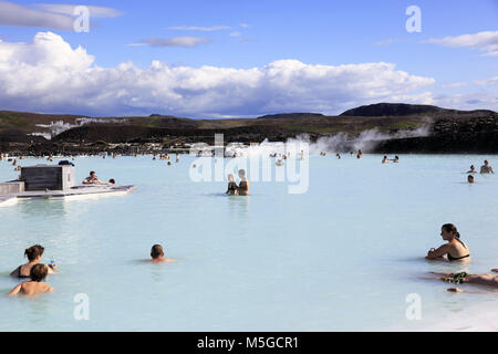 Visitors relax in the geothermal spa of the Blue Lagoon with Svartsengi geothermal power plant in the background.near Reykjavik.Iceland Stock Photo