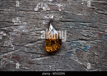 Green amber pendant on a wooden background Stock Photo