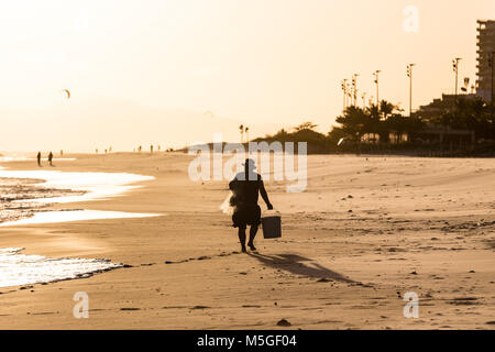 Silhouette of worker walking on the beach during sunset in Barra da Tijuca beach, Rio de janeiro Stock Photo