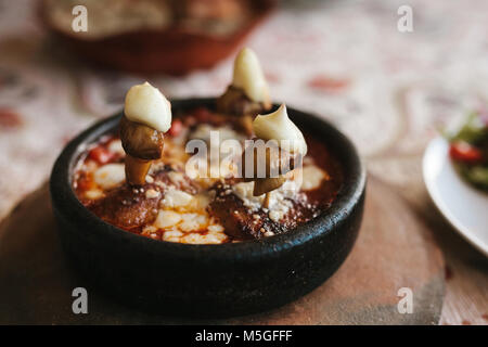 Dish with mushrooms and white sauce in bowl on wooden stand. Restaurant menu. Stock Photo