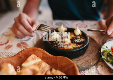 Man's hands holding cutlery - preparing to eat dish with mushrooms at table in cafe Stock Photo
