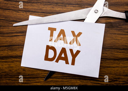 Hand writing text caption inspiration showing Tax Day. Business concept for Income taxation Refund Written on note, wooden with colourful scissors mea Stock Photo