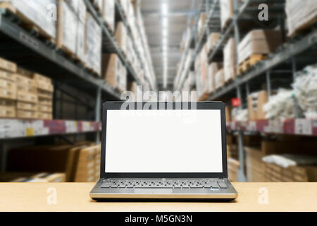 Laptop with white blank screen on brown wooden desk and blurred warehouse store background Stock Photo