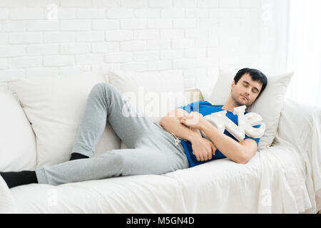 Young handsome man slepping and hugging LOVE alphabet in sofa in bedroom at home. Young single man want someone to love. Stock Photo