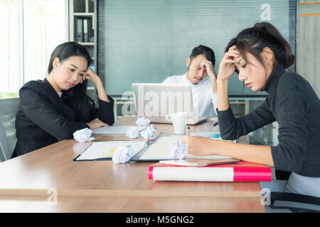 Group of unhappy Asian business people in casual suit sitting in business meeting room and looking strain. Stock Photo