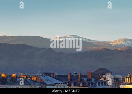 Scenic hills of Snowdonia dusted in snow above roof tops of victorian building. Llandudno, North Wales. UK Stock Photo