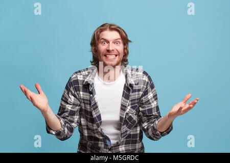 Delight. Beautiful male half-length front portrait isolated on blue studio backgroud. Young, emotional, smiling, surprised man standing. Human emotion Stock Photo