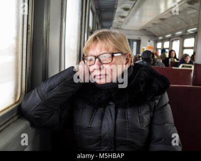 midle aged caucasian woman sits near the window in the train Stock Photo