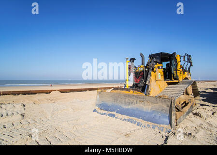 Bulldozer used for sand replenishment / beach nourishment to make wider beaches to reduce storm damage to coastal structures along the Belgian coast Stock Photo